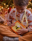 A child holds a yellow silicone bag with a bee design and a white heart.