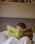 A child reads an open activity book titled "Through My Lens" with a butterfly illustration.