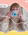 A child holding and aiming the Kidamento Model A Cinnamoroll kids' digital camera, with playful graphic overlays and the caption “Mini in size, mega in magic!”.