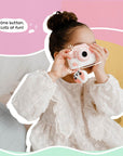 Little girl using the Kidamento Meowie the Cat digital camera, pressing the shutter button to capture fun moments with its adorable pink silicone design.