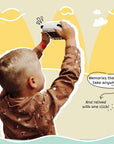 Boy holding up kiimento Model P Panda kids camera, capturing memories outdoors with playful illustrated background.