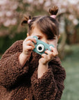 Young girl using kiimento Bear Digital Camera Model C outdoors – green bear-shaped kids camera ages 3 to 6