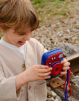 Child holding a toy camera with Spider-Man design outdoors