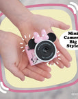 Minnie Mouse mini camera with pink bow and ears holding by kid's hands.