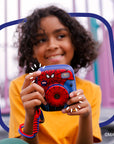 A child holds a blue and red Spider-Man instant print camera.