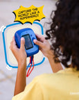A child holds a blue Spider-Man instant print camera.