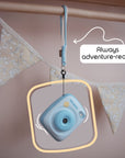 Sky blue instant print camera with a wrist strap hanging from a wooden rod.