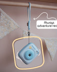 Sky blue instant print camera with a wrist strap hanging from a wooden rod.
