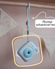 Sky blue instant print camera with a wrist strap hanging from a wooden rod.