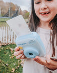 Girl holding kiimento Sky Blue Print Pro Camera Model P2 printing a photo outdoors