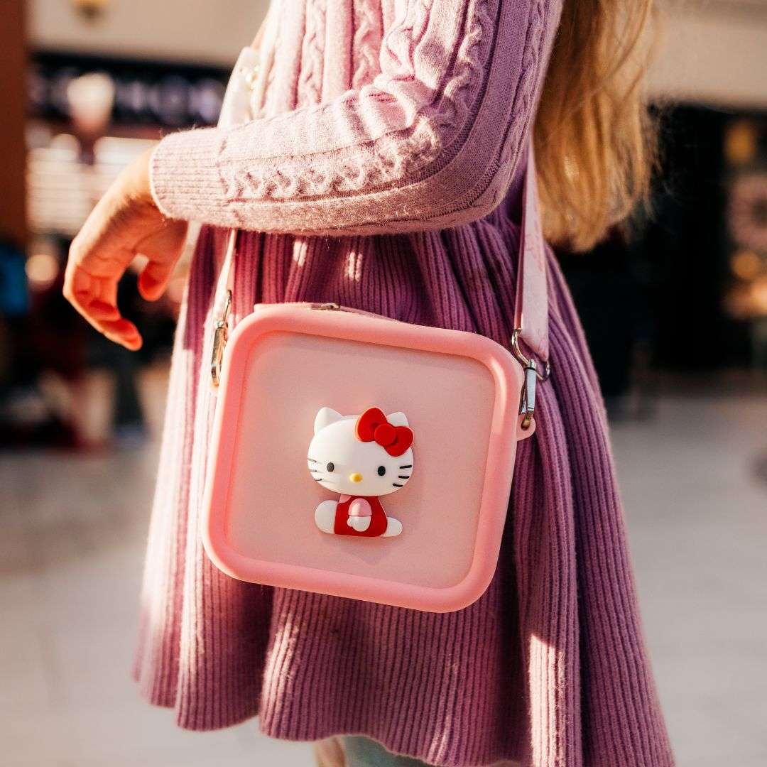 A child wears a pink Hello Kitty silicone bag with a red bow.