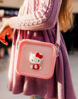 A child wears a pink Hello Kitty silicone bag with a red bow.