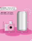 A pink Hello Kitty mini camera shown next to a standard soda can for size comparison.
