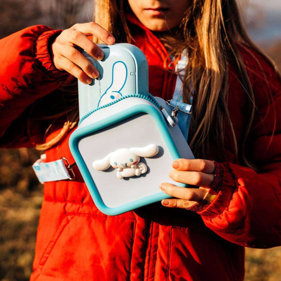 A child in a red jacket holds a light blue silicone Cinnamoroll bag.