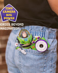 Digital Buzz Lightyear mini camera with green and purple body, tucked into a pocket for size and use reference.