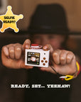 Rear view of the digital Jesie mini camera showing the digital LCD screen, a brown directional pad, brown buttons for navigation, themed filters and the selfie of a happy kid. 