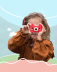 Young girl holding Kidamento Model C Fox kids camera up to her eyes, ready to take a photo