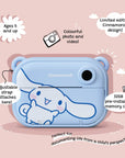 Front view of the Kidamento Model P Cinnamoroll kids’ digital camera on a pink background, with callouts showing its features: ages 5 and up, colorful photo and video, limited edition Cinnamoroll design, 32GB memory, and adjustable strap attachment.