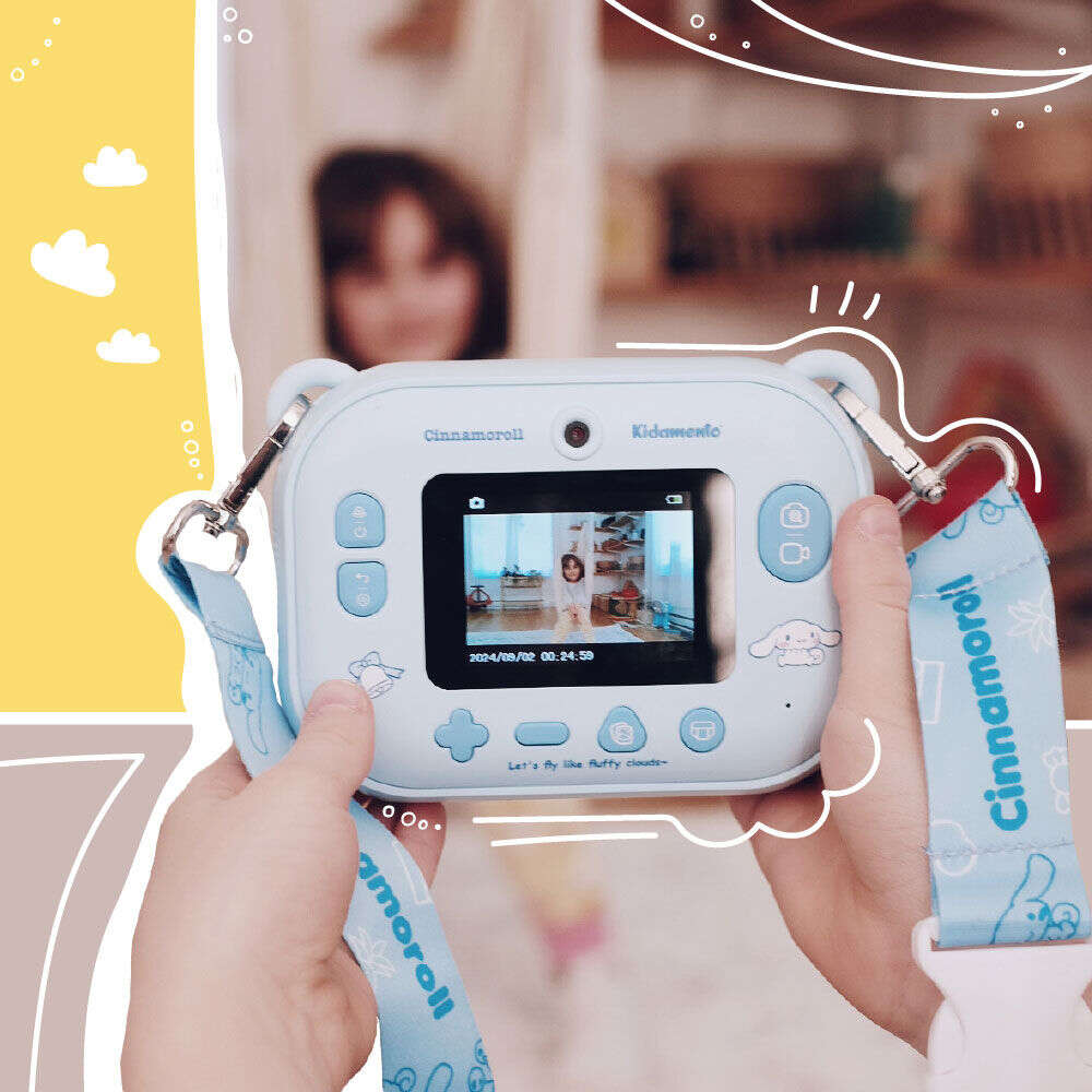Close-up of a child holding the Kidamento Model P Cinnamoroll camera, showing a preview screen with a girl posing for a photo. The lanyard strap with Cinnamoroll branding is visible, set against a cheerful background with illustrated accents.