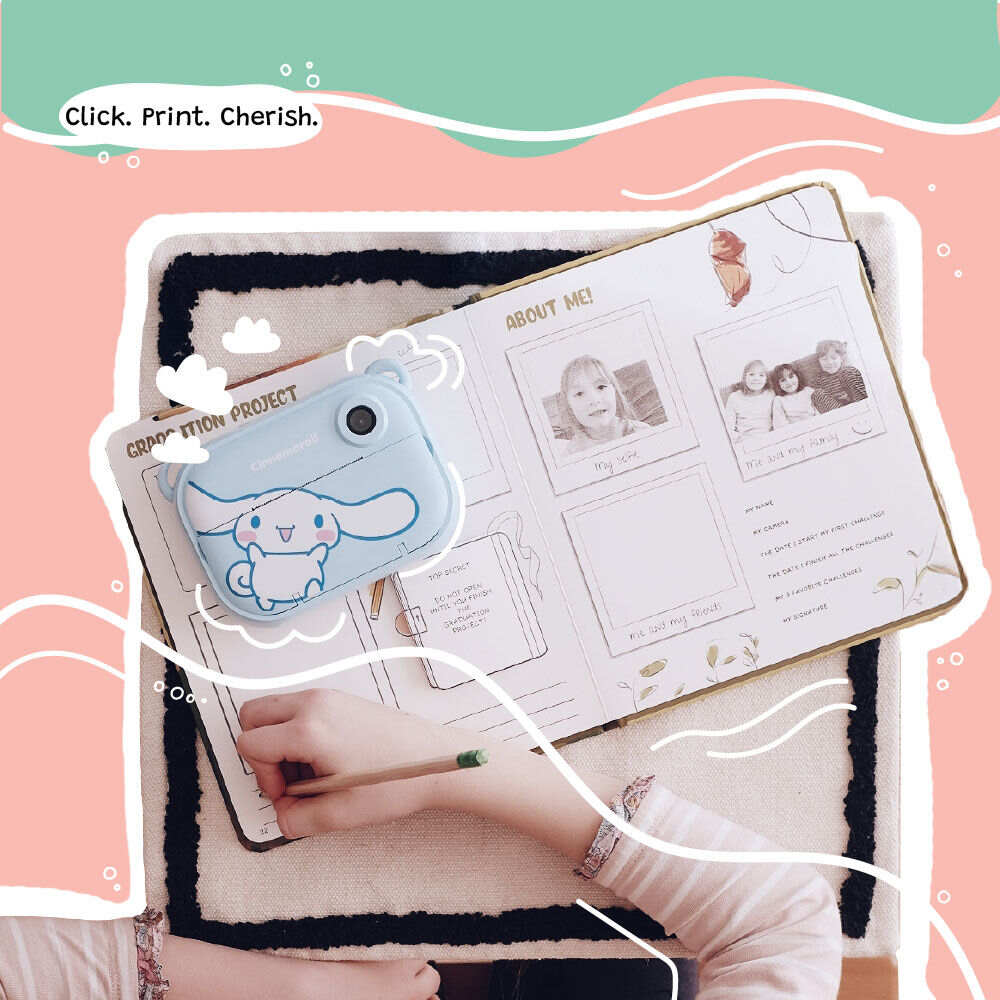 Lifestyle image of the Kidamento Model P Cinnamoroll kids’ digital camera placed on an open scrapbook filled with printed photos. A child's hand is seen writing in the book, capturing a sweet moment of creativity and memory-keeping.