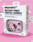 Retail packaging of the Kidamento Hello Kitty Model P instant print digital camera, featuring a window showing the pastel pink camera with Hello Kitty’s face. The box highlights gift readiness, ink-free and cost-effective printing, and memory-making appeal. Tagline at the bottom reads: “Joy in every box. Memories in every click!”