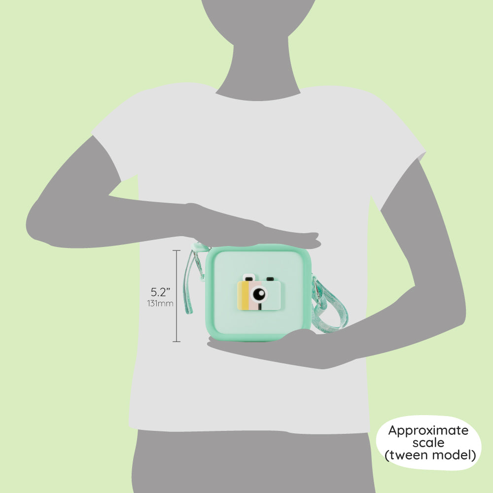 A green silicone camera bag with a strap, shown to scale against a tween model.