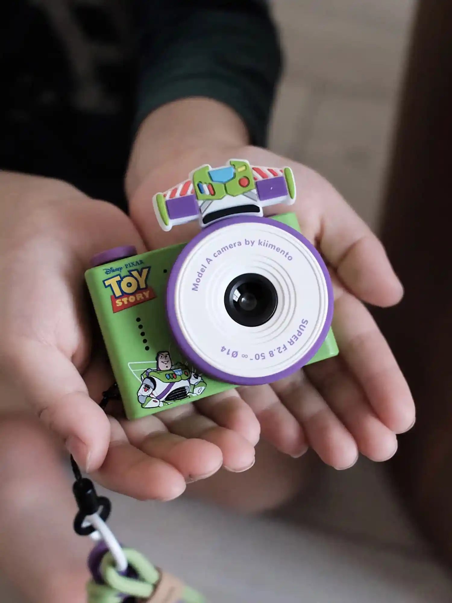 Toy Story-themed camera and book held in hands with a blurred background