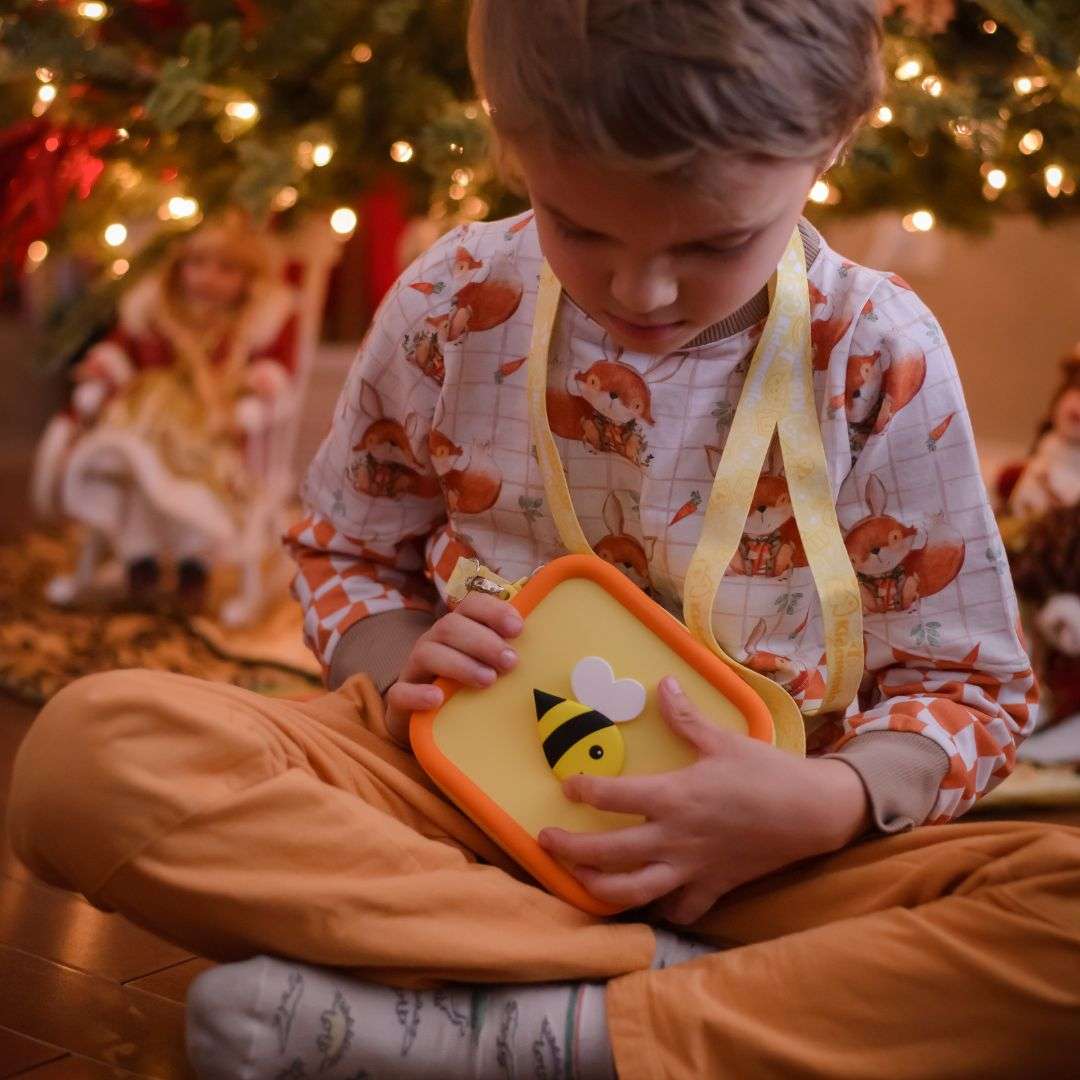 A child holds a yellow silicone bag with a bee design.