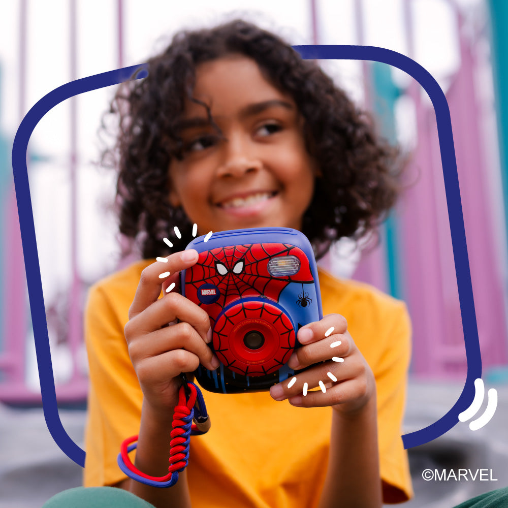 A child holds a blue and red Spider-Man instant print camera.
