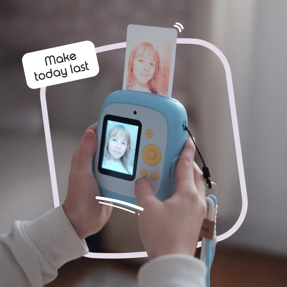 Sky blue instant print camera with a photo coming out of the top.