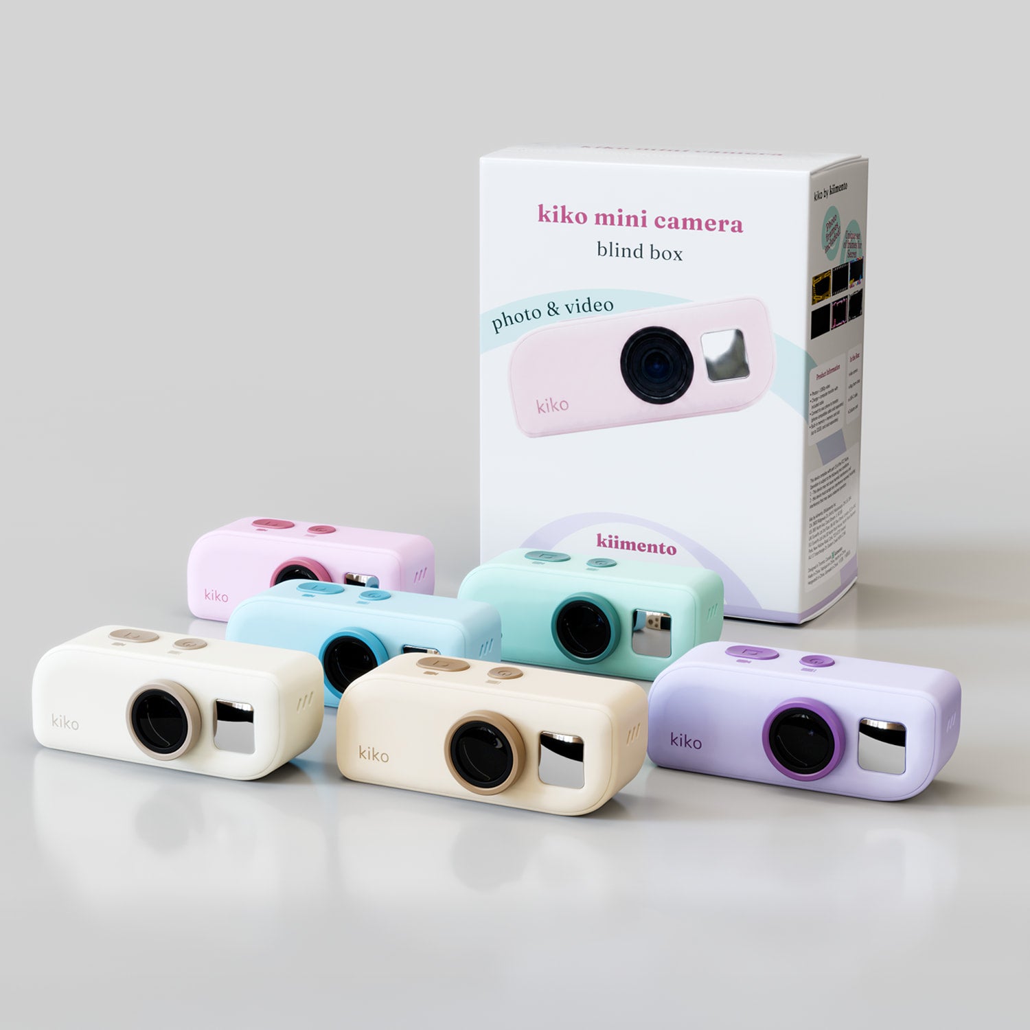 All six kiko Mini Camera non-licensed colorways (pink, blue, mint, cream/white, tan/golden, lavender) grouped together in front of the retail packaging, showing each camera's solid pastel finish.